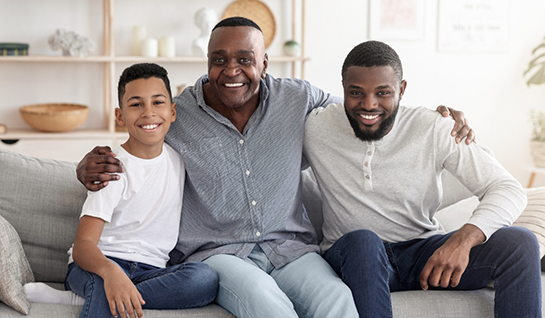 Older man sitting with younger man and child on couch