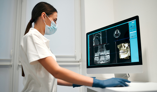 Female dentist with mask looking at X ray on computer