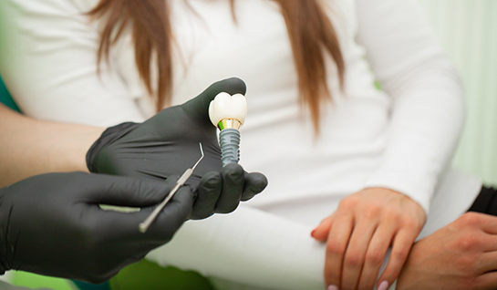 Close-up of gloved hand holding a dental implant in Riverdale Park