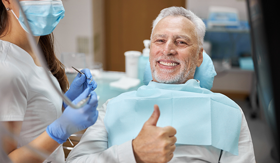 Older male dental patient giving thumbs up