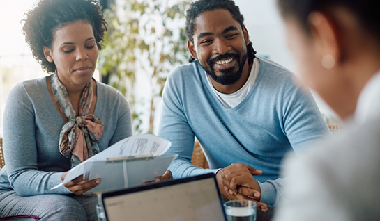 Man and woman sitting together while woman looks at clipboard