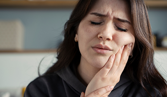 Close-up of woman rubbing her jaw in pain