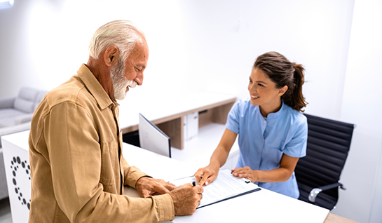 Female dental team member helping male patient fill out form