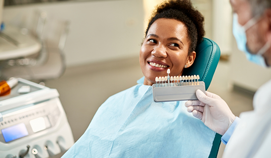 Woman in dental chair having teeth shade matched for veneers