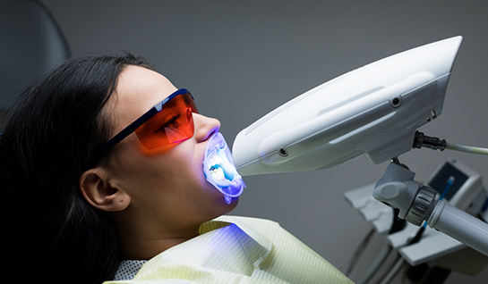 Dental patient having light shined on teeth for teeth whitening
